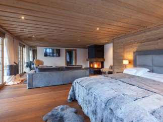 Experience luxury in this stunning bedroom featuring a cozy fireplace and a plush, inviting bed.