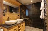 This luxurious bathroom features a rustic wooden vanity with two elegant vessel sinks.