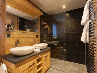 This luxurious bathroom features a rustic wooden vanity with two elegant vessel sinks.