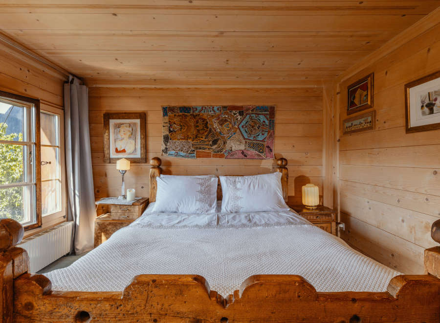 Experience rustic charm in this cozy bedroom, featuring warm wooden walls and a comfortable bed.