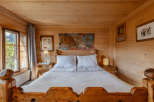 Experience rustic charm in this cozy bedroom, featuring warm wooden walls and a comfortable bed.