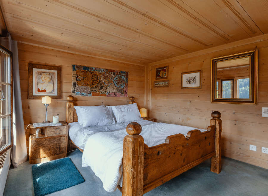 This cozy bedroom features a rustic wooden bed frame and walls, creating a warm and inviting atmosphere.