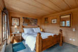 This cozy bedroom features a rustic wooden bed frame and walls, creating a warm and inviting atmosphere.