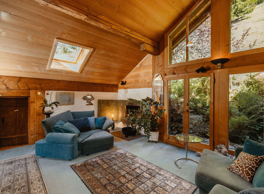 Step into a cozy living space with a unique wooden ceiling and abundant natural light.