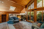 Step into a cozy living space with a unique wooden ceiling and abundant natural light.