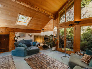 Step into a cozy living space with a unique wooden ceiling and abundant natural light.