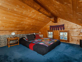 Cozy bedroom in a wooden cabin with a unique, colorful quilt.