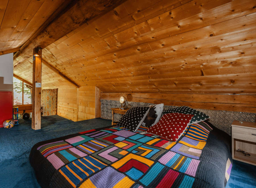 Cozy cabin bedroom with a unique, colorful quilt.