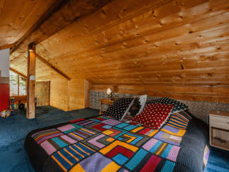 Cozy cabin bedroom with a unique, colorful quilt.