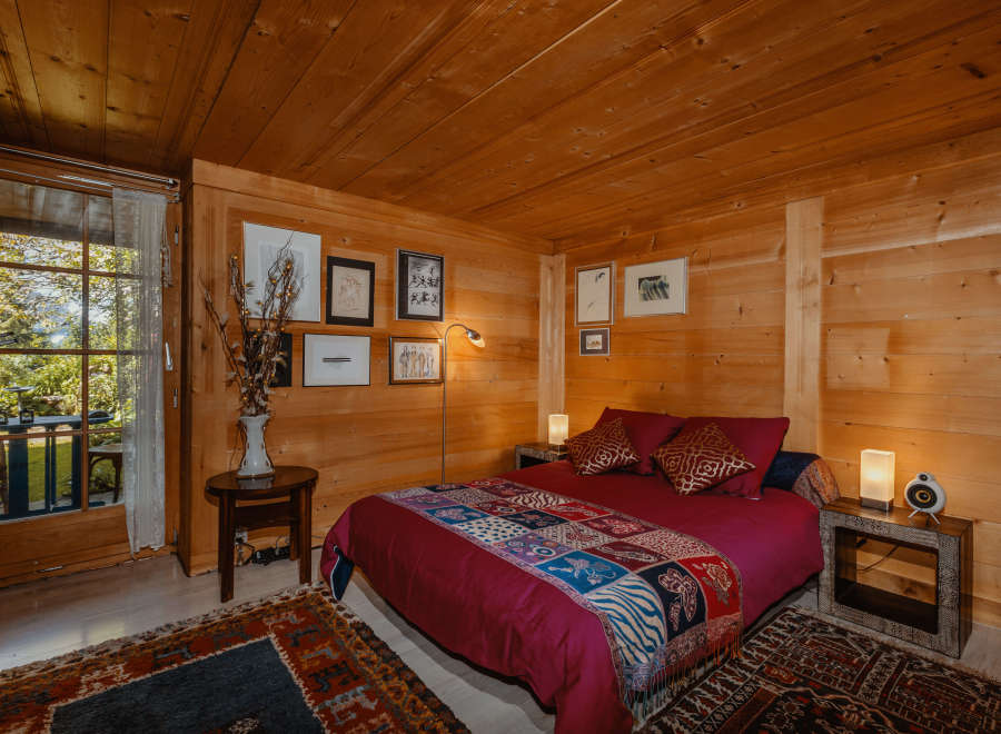 Cozy bedroom with wooden walls and ceiling, creating a warm and inviting atmosphere.