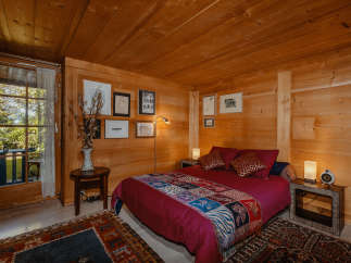 Cozy bedroom with wooden walls and ceiling, creating a warm and inviting atmosphere.