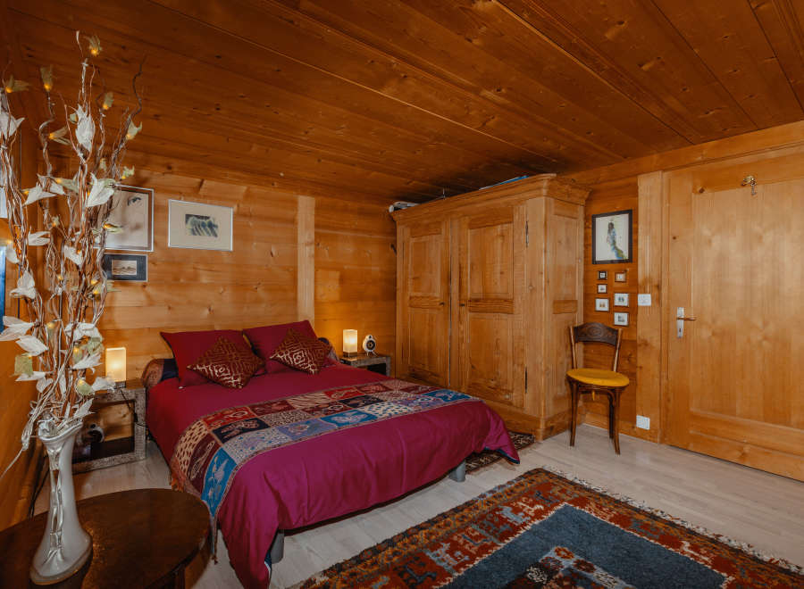 Cozy bedroom with wooden walls and ceiling, creating a warm and inviting atmosphere.