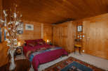 Cozy bedroom with wooden walls and ceiling, creating a warm and inviting atmosphere.