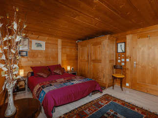 Cozy bedroom with wooden walls and ceiling, creating a warm and inviting atmosphere.