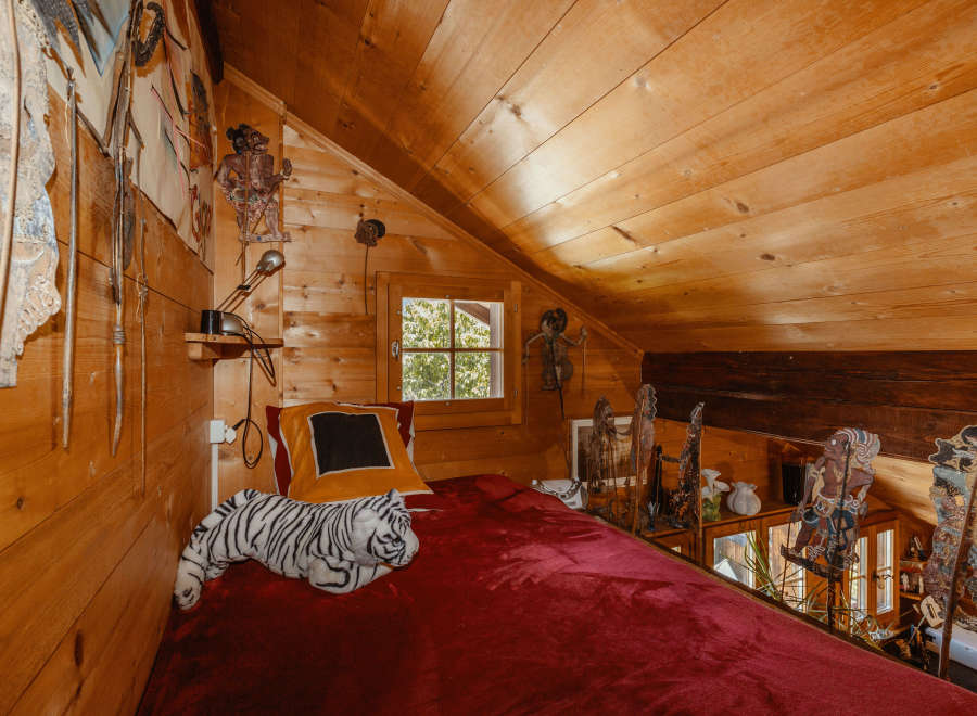 Cozy attic bedroom with wooden walls and ceiling.