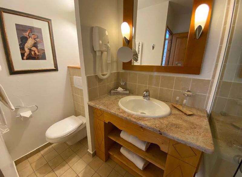 This bathroom features a stylish vanity with a marble countertop and wooden accents, creating a warm and inviting atmosphere.