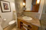 This bathroom features a stylish vanity with a marble countertop and wooden accents, creating a warm and inviting atmosphere.