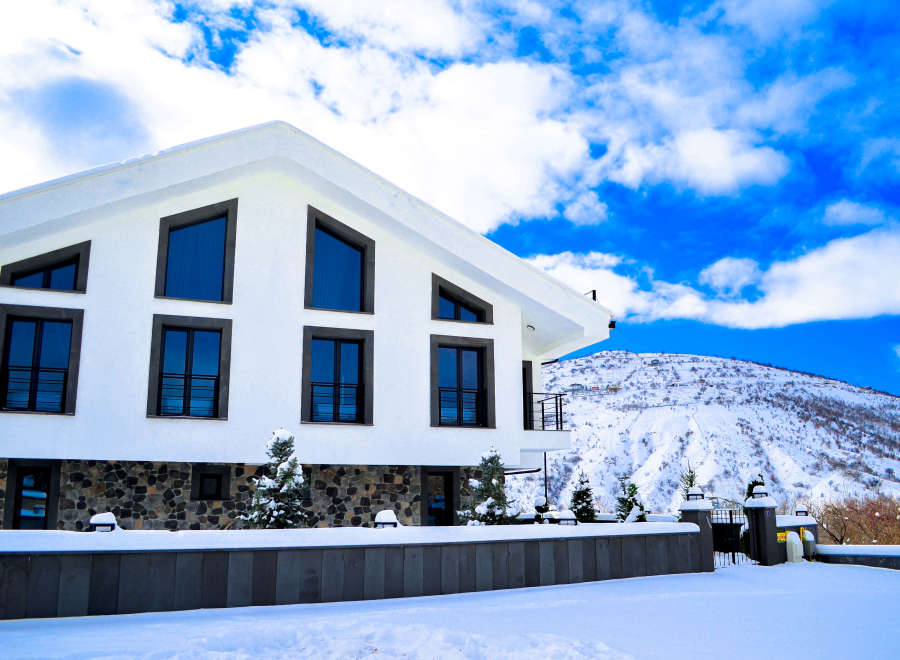 This stunning modern home boasts a sleek white exterior and unique window designs.