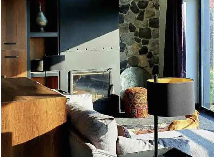 Discover the charm of this stunning property, featuring a cozy living room with a stone fireplace and a stylish sofa.