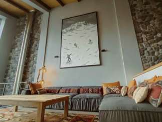 Experience the charm of this cozy living space, featuring a stunning mountain-themed artwork and a comfortable sectional sofa.