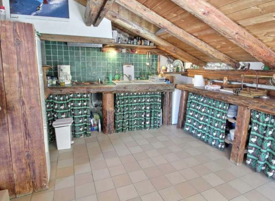Rustic mountain kitchen with exposed wooden beams and charming green tile backsplash.