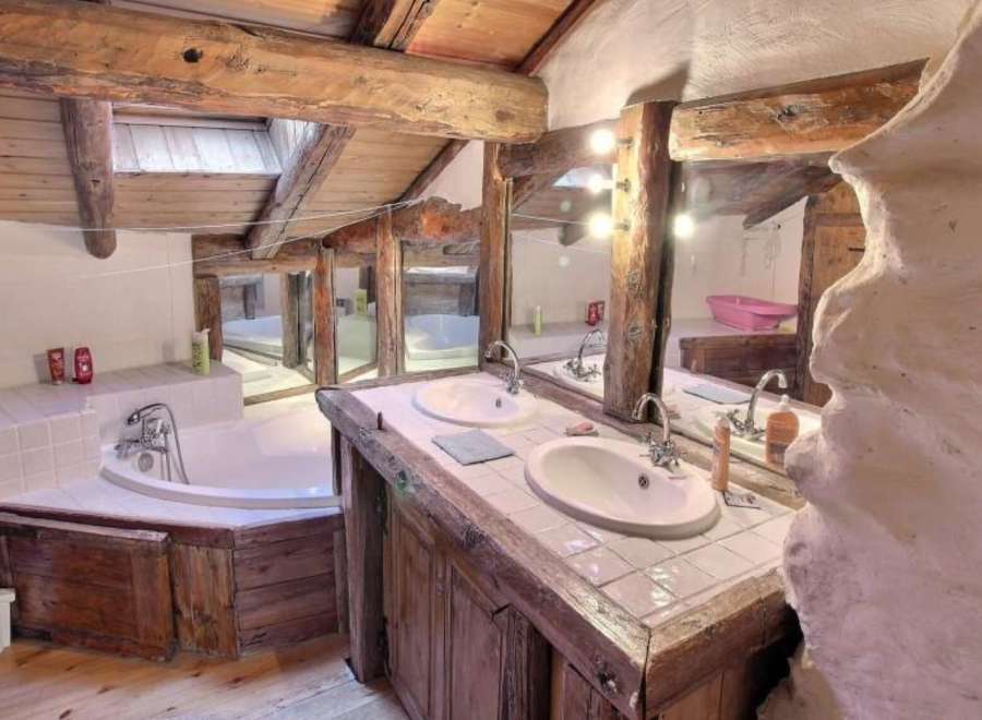 Rustic bathroom with exposed wooden beams and a unique stone feature wall.