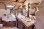 Rustic bathroom with exposed wooden beams and a unique stone feature wall.