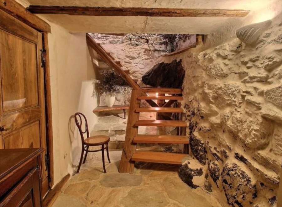 Discover the charm of this unique property, featuring a rustic wooden staircase descending into a captivating stone cellar.