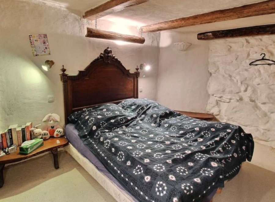 Charming bedroom with exposed wooden beams and stone walls.