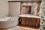 Rustic bathroom with a large corner bathtub and double vanity.