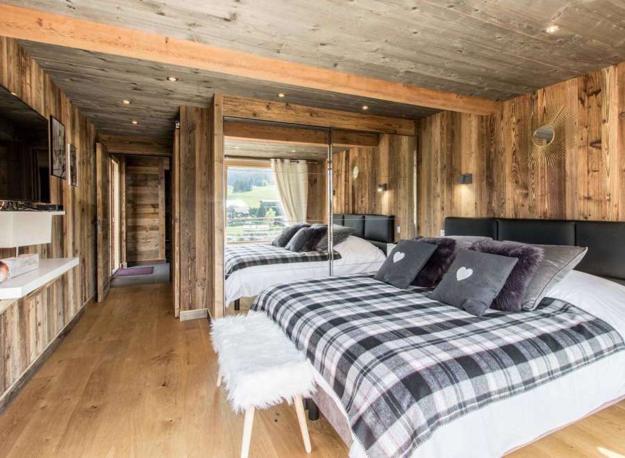 Experience rustic charm in this cozy bedroom, featuring warm wooden walls and a stylish plaid blanket.
