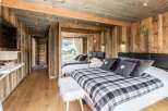 Experience rustic charm in this cozy bedroom, featuring warm wooden walls and a stylish plaid blanket.