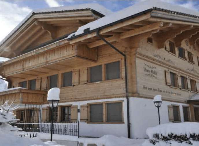 This charming wooden chalet, nestled in a snowy landscape, exudes warmth and rustic elegance.