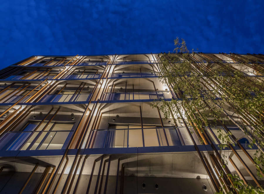 This modern apartment building features a unique architectural design with wooden slats creating a striking facade.