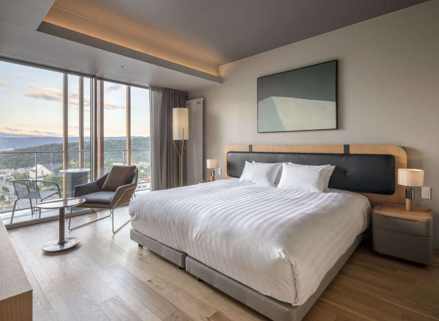 Wake up to breathtaking views from this luxurious hotel room, featuring a king-size bed with crisp white linens and a plush headboard.