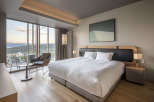 Wake up to breathtaking views from this luxurious hotel room, featuring a king-size bed with crisp white linens and a plush headboard.
