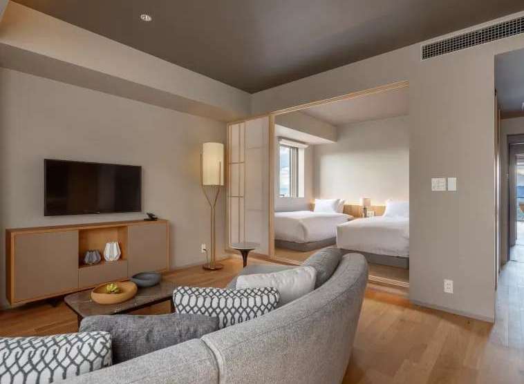 This modern hotel room boasts a spacious layout with a comfortable seating area and a large flat-screen TV.