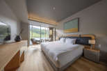 This hotel room boasts a king-size bed with crisp white linens, offering stunning mountain views from its large window.