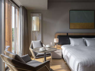This hotel room boasts a modern design with floor-to-ceiling windows offering scenic views, creating a bright and airy atmosphere.