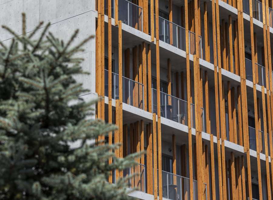 This modern apartment building boasts a unique architectural design, featuring a striking contrast between sleek concrete and warm wood accents.