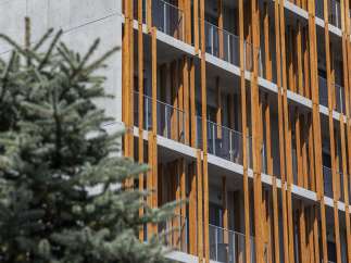 This modern apartment building boasts a unique architectural design, featuring a striking contrast between sleek concrete and warm wood accents.
