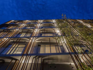 This modern apartment building features a unique architectural design with wooden slats creating a striking facade.