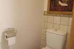 This cozy bathroom features a classic toilet and a stylish painting, creating a comfortable and inviting atmosphere.