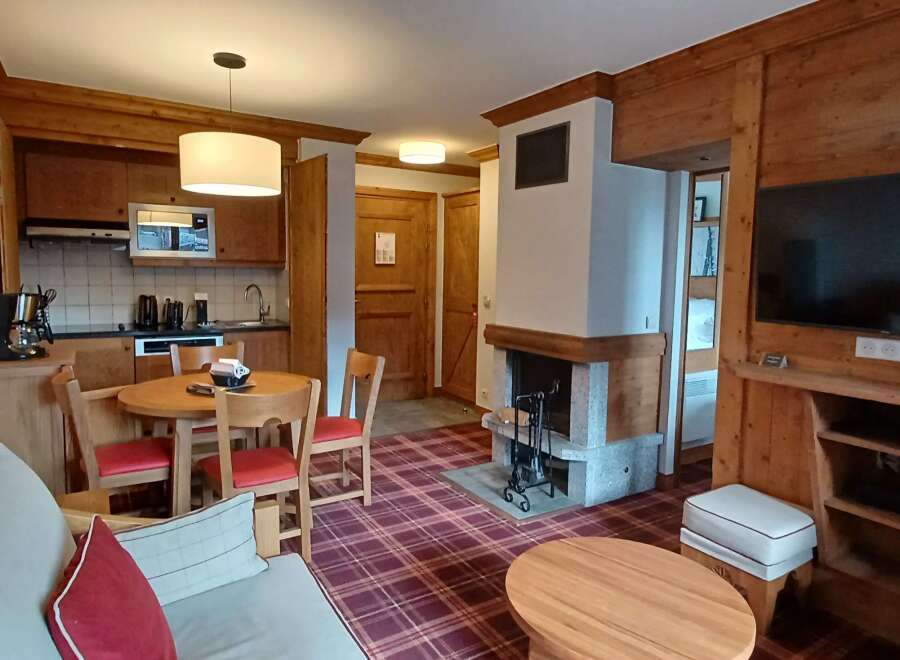 Experience cozy living in this charming apartment featuring a rustic wooden interior and a warm plaid carpet.