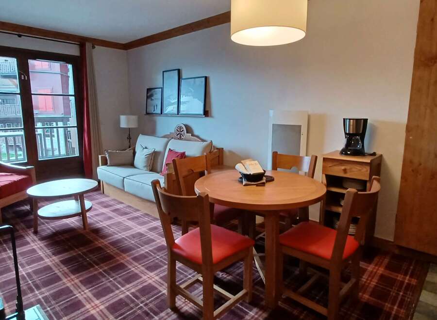 Experience cozy living in this charming apartment, featuring a comfortable sofa and a dining area perfect for meals or work.