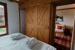 Experience rustic charm and modern comfort in this inviting bedroom, featuring a plush bed adorned with two white bathrobes, perfect for unwinding.