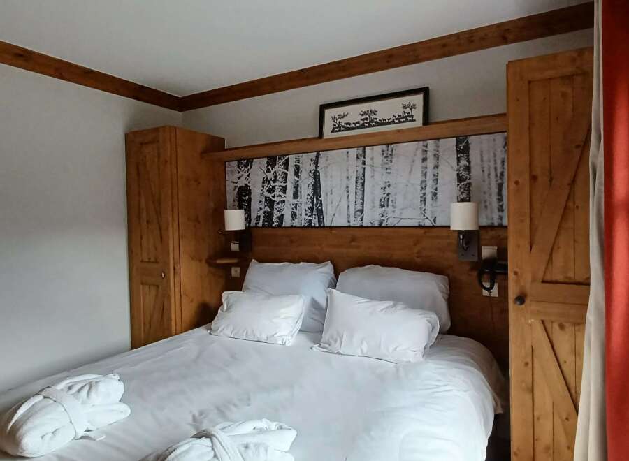 Experience rustic charm and comfort in this beautifully appointed bedroom, featuring a plush king-sized bed adorned with crisp white linens and cozy bathrobes.