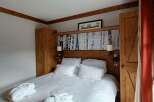 Experience rustic charm and comfort in this beautifully appointed bedroom, featuring a plush king-sized bed adorned with crisp white linens and cozy bathrobes.