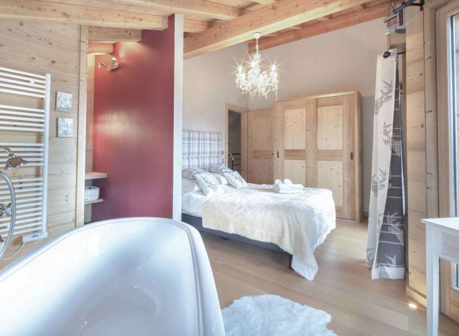 Experience luxury in this stunning property featuring a cozy bedroom with a plush bed and elegant chandelier.