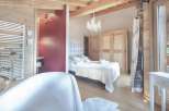 Experience luxury in this stunning property featuring a cozy bedroom with a plush bed and elegant chandelier.